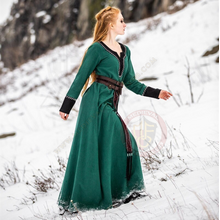 Woman walking in the snow wearing a green viking style dress